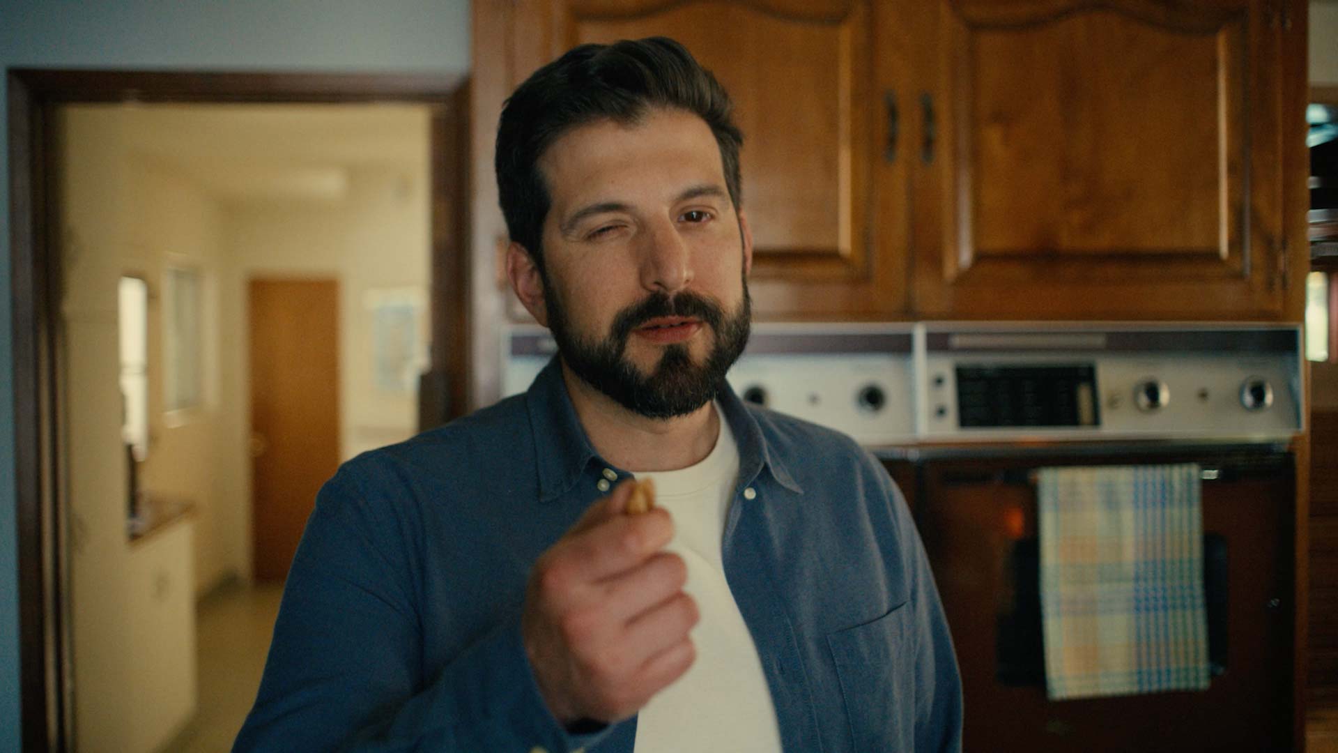 Still frame from "Squirrel" tv spot of bearded Dad holding up a pecan while nodding and winking.