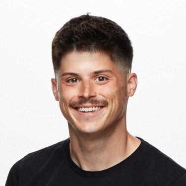 Photo of Elijah Kleinsmith – a dark-haired lightly mustachioed but intelligent-appearing young man wearing a black t-shirt in front of a white background